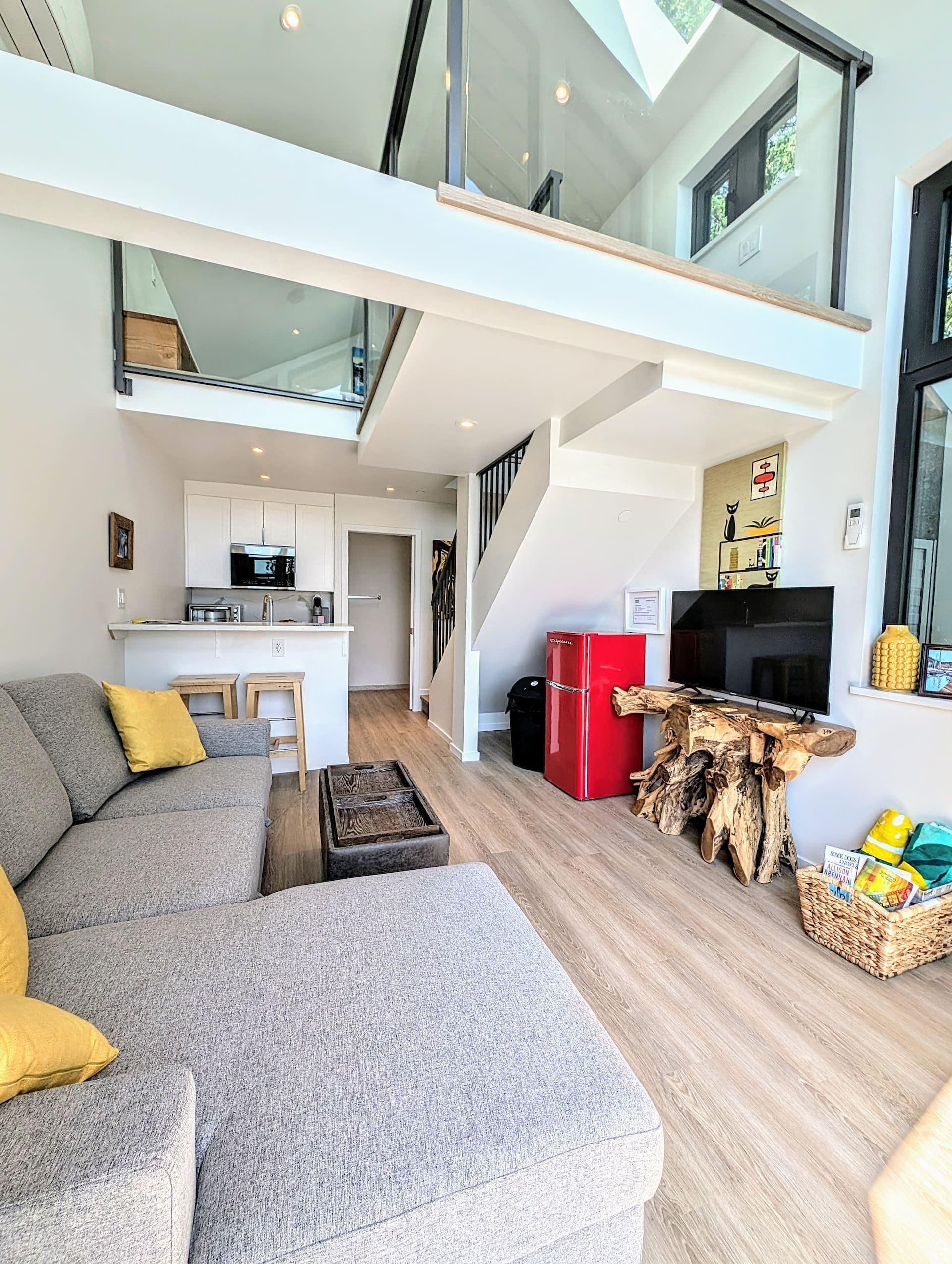 Main-floor living room with sectional sofa, kitchenette, and loft above