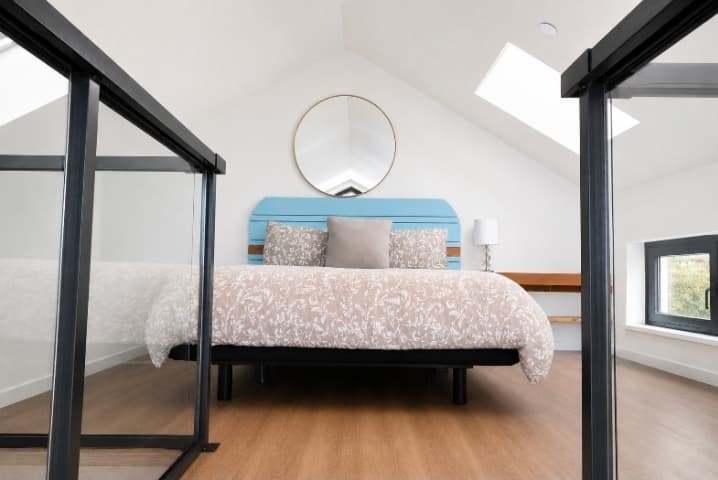 Loft bedroom with adjustable queen bed and round skylight mirror